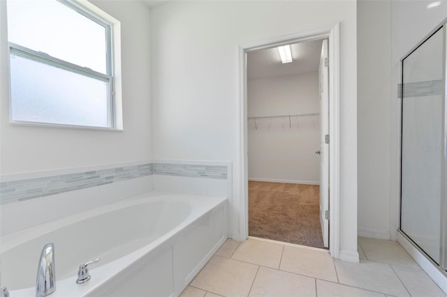 bathroom featuring a garden tub, a shower stall, a walk in closet, and tile patterned floors