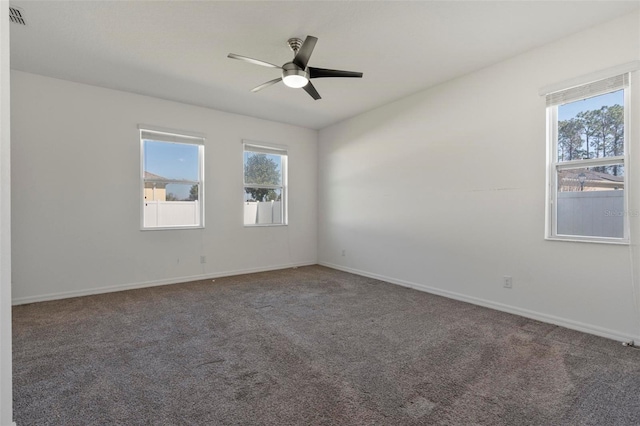 carpeted spare room featuring a ceiling fan, a healthy amount of sunlight, visible vents, and baseboards