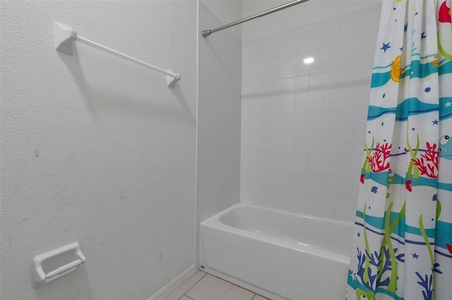 bathroom featuring tile patterned flooring, shower / bath combo, and baseboards