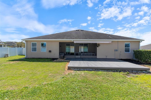 back of house featuring fence, a deck, a lawn, and stucco siding