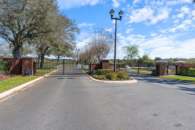 view of street with a gate, curbs, a gated entry, and street lights