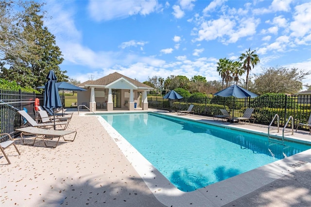 pool with a patio area, fence, and an outdoor structure