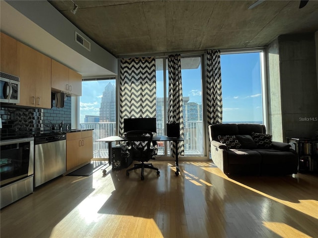 interior space with expansive windows, visible vents, and wood finished floors