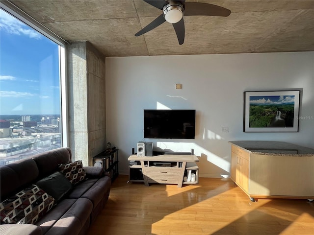 living room featuring a wall of windows, ceiling fan, baseboards, and wood finished floors