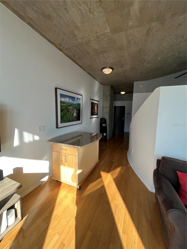 corridor with baseboards and wood finished floors