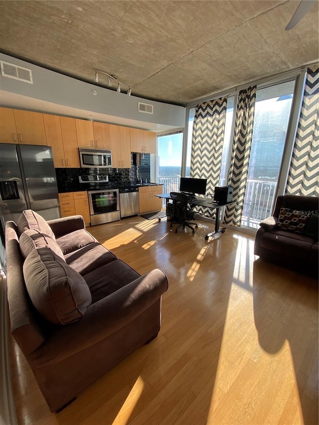 living area featuring rail lighting, expansive windows, visible vents, and light wood finished floors