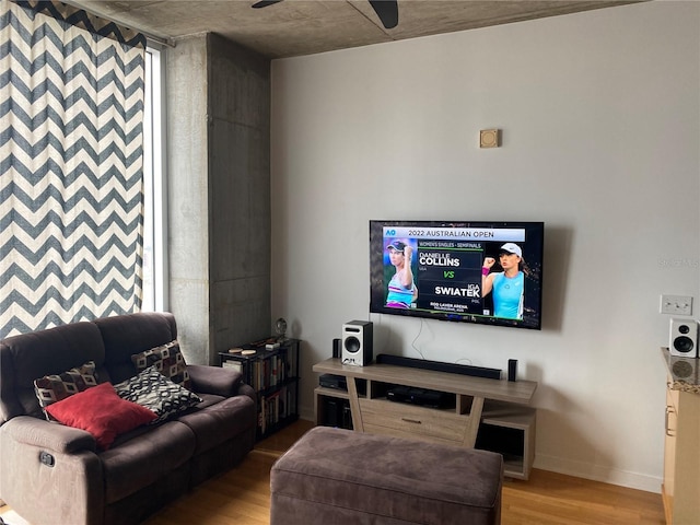 living area featuring ceiling fan, baseboards, and wood finished floors