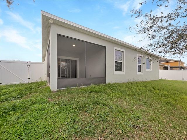15120 Zenith Ave, Mascotte, FL 34753 - rear view of house featuring a sunroom, a gate, fence, a yard, and stucco siding