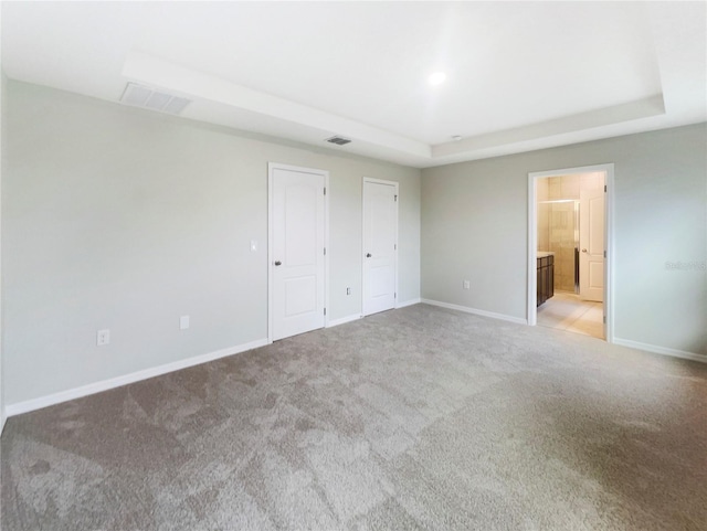 15120 Zenith Ave, Mascotte, FL 34753 - unfurnished bedroom with a tray ceiling, two closets, visible vents, light carpet, and baseboards
