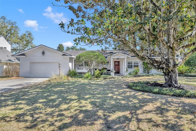 ranch-style house featuring a front yard, covered porch, driveway, and an attached garage