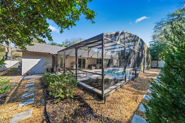 rear view of property featuring an outdoor pool, a lanai, fence, a patio area, and stucco siding