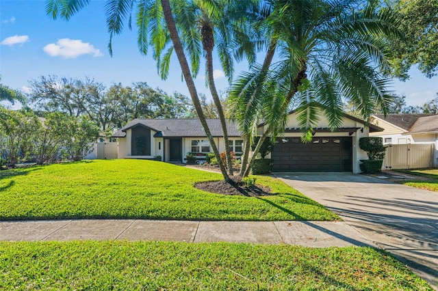 ranch-style house featuring stucco siding, a front yard, a gate, a garage, and driveway