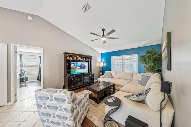 living room featuring light tile patterned floors, baseboards, visible vents, a ceiling fan, and vaulted ceiling