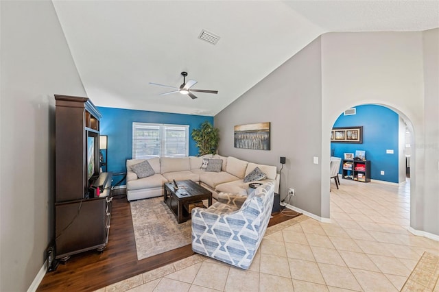 living area featuring arched walkways, ceiling fan, light tile patterned flooring, visible vents, and baseboards