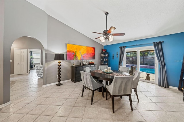 dining area featuring arched walkways, ceiling fan, light tile patterned flooring, and baseboards