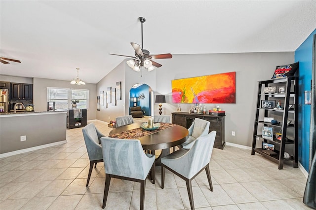 dining area featuring arched walkways, lofted ceiling, light tile patterned flooring, baseboards, and ceiling fan with notable chandelier