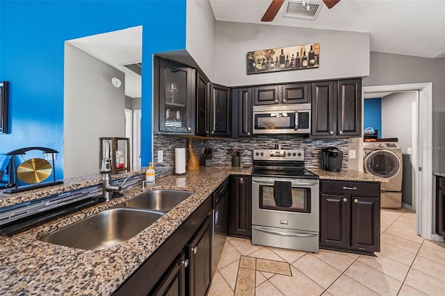 kitchen with stone countertops, stainless steel appliances, a sink, visible vents, and washer / dryer