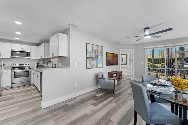 kitchen featuring appliances with stainless steel finishes, light wood-type flooring, light stone counters, and white cabinetry