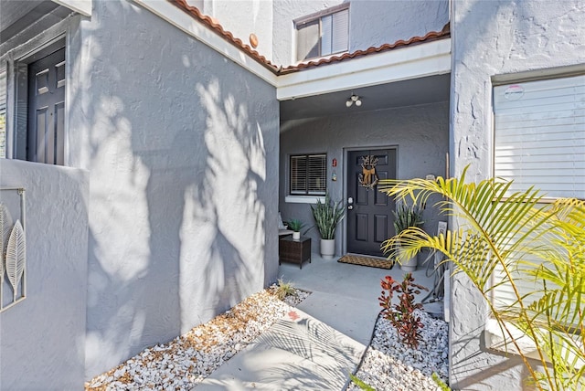 property entrance with a tile roof and stucco siding