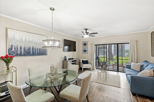 dining area featuring ceiling fan with notable chandelier, ornamental molding, wood finished floors, and baseboards