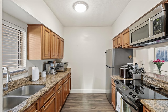 kitchen with brown cabinets, stainless steel microwave, black range with electric stovetop, dark wood-type flooring, and a sink