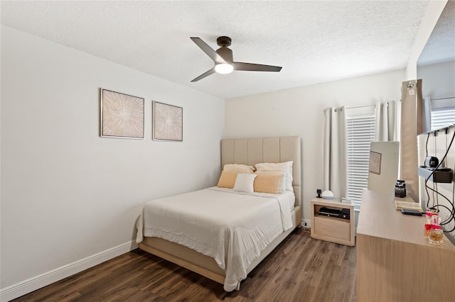 bedroom featuring ceiling fan, a textured ceiling, baseboards, and wood finished floors