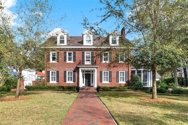 colonial inspired home featuring brick siding and a front yard