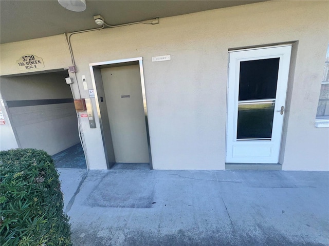 entrance to property featuring elevator and stucco siding