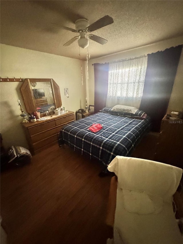 bedroom with a ceiling fan, a textured ceiling, and wood finished floors