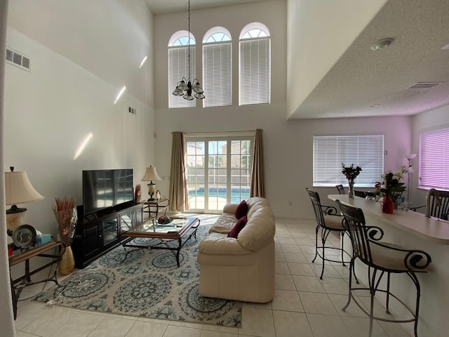 living room with a wealth of natural light, tile patterned flooring, visible vents, and a notable chandelier