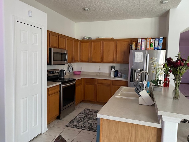 kitchen featuring appliances with stainless steel finishes, light countertops, a sink, and light tile patterned floors