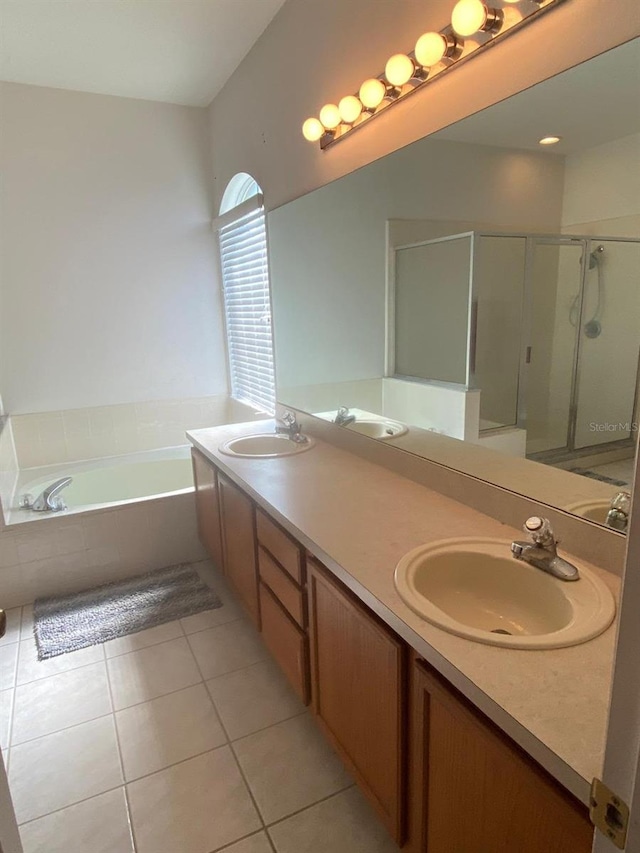 bathroom with double vanity, a garden tub, a shower stall, and a sink