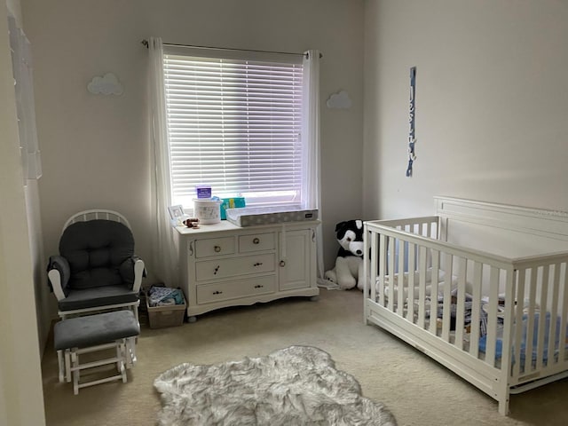 bedroom with light carpet and a nursery area