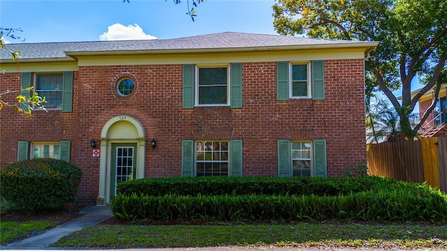 view of front of home featuring fence and brick siding