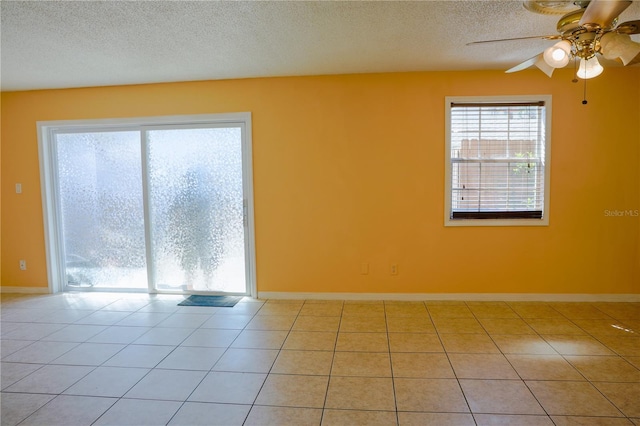 spare room with light tile patterned floors, ceiling fan, a textured ceiling, and a wealth of natural light