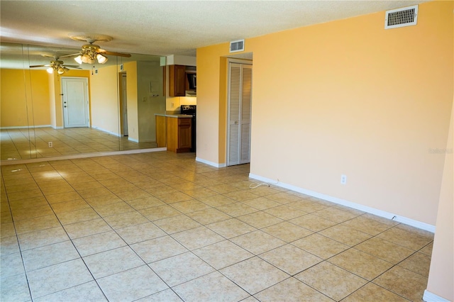 empty room featuring a textured ceiling, visible vents, a ceiling fan, and light tile patterned flooring