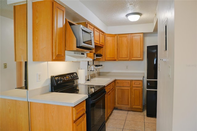 kitchen with light tile patterned floors, stainless steel microwave, black electric range oven, a sink, and exhaust hood