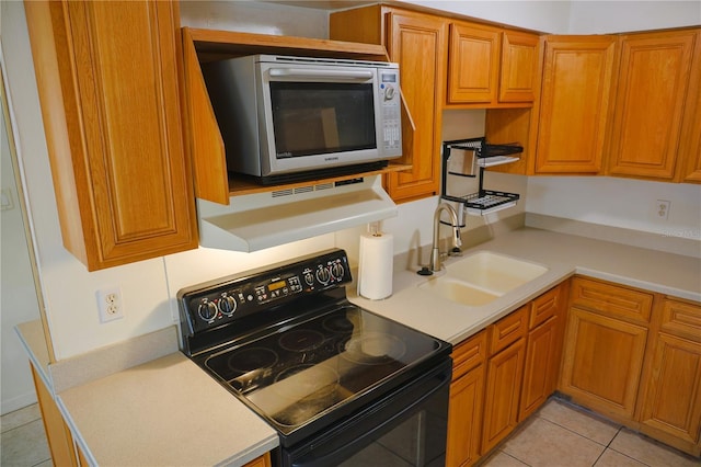 kitchen featuring a sink, stainless steel microwave, brown cabinets, and black range with electric stovetop