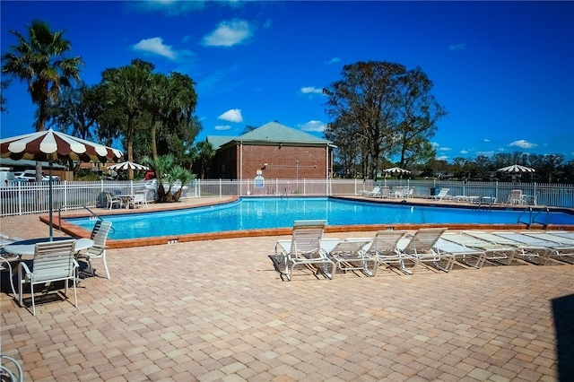 community pool with a patio and fence