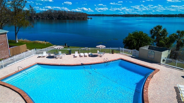 pool featuring a water view, fence, and a patio