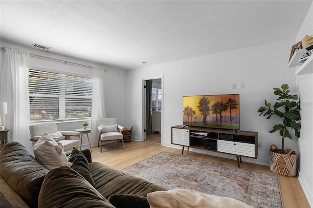 living room with visible vents, baseboards, and wood finished floors