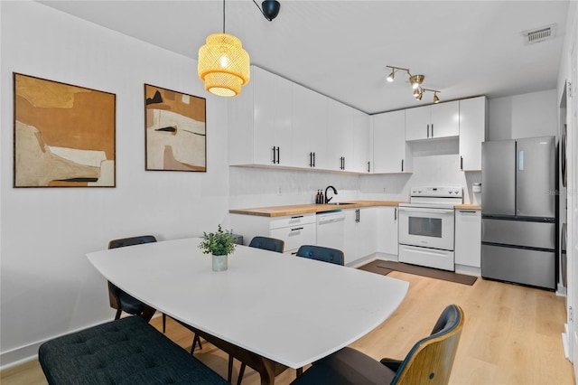 kitchen with light wood-type flooring, visible vents, decorative light fixtures, white appliances, and white cabinets