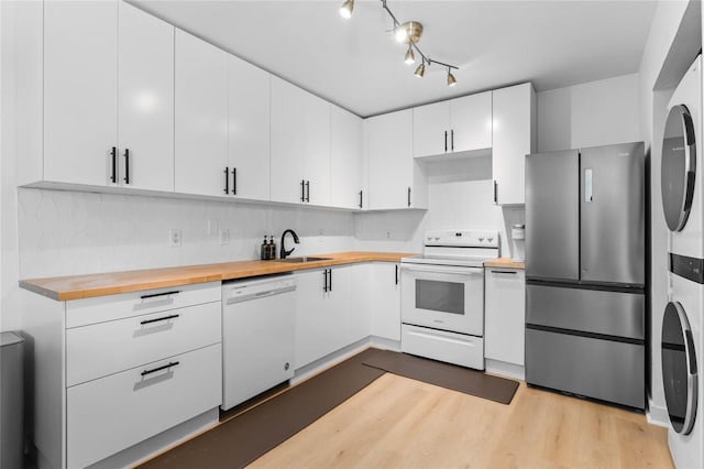 kitchen with a sink, white appliances, light wood-style floors, white cabinets, and butcher block counters