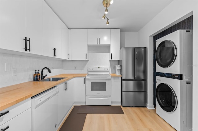 kitchen with a sink, white appliances, stacked washer and clothes dryer, and butcher block countertops