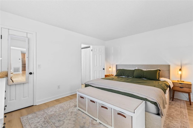 bedroom featuring light wood finished floors, visible vents, and baseboards