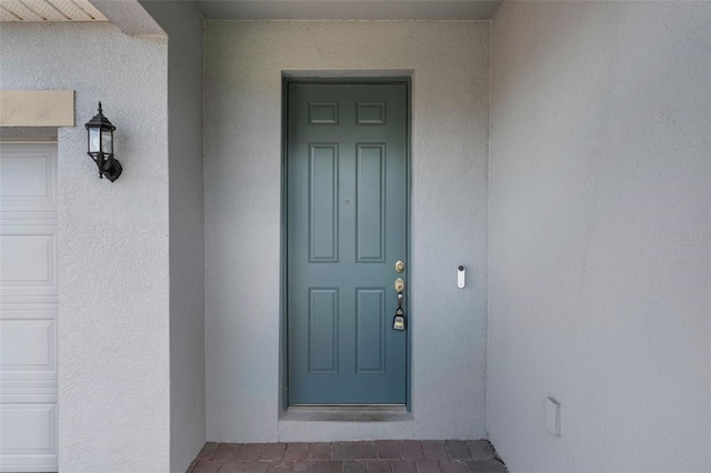 doorway to property with a garage and stucco siding