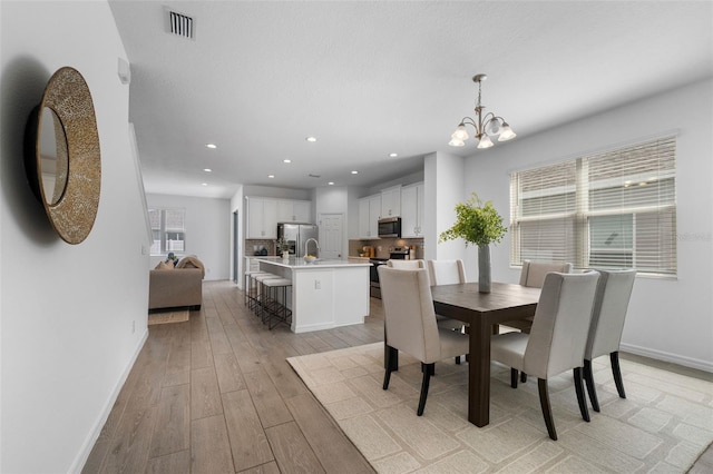 dining room featuring baseboards, recessed lighting, light wood-style flooring, and a notable chandelier