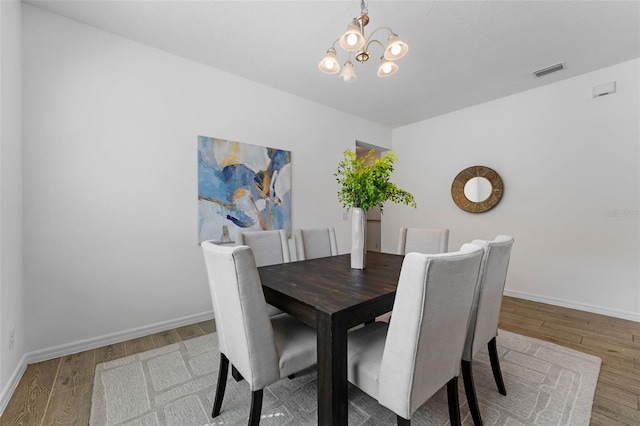 dining room featuring a chandelier, visible vents, baseboards, and wood finished floors