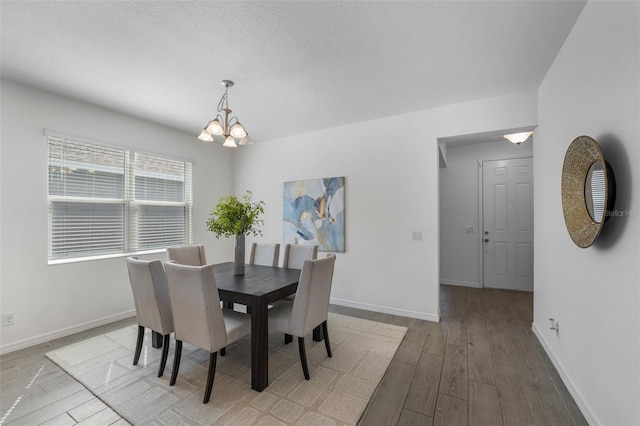 dining space with a chandelier, wood finished floors, and baseboards