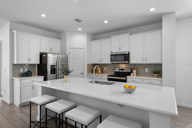 kitchen featuring appliances with stainless steel finishes, a sink, light wood-style flooring, and white cabinets